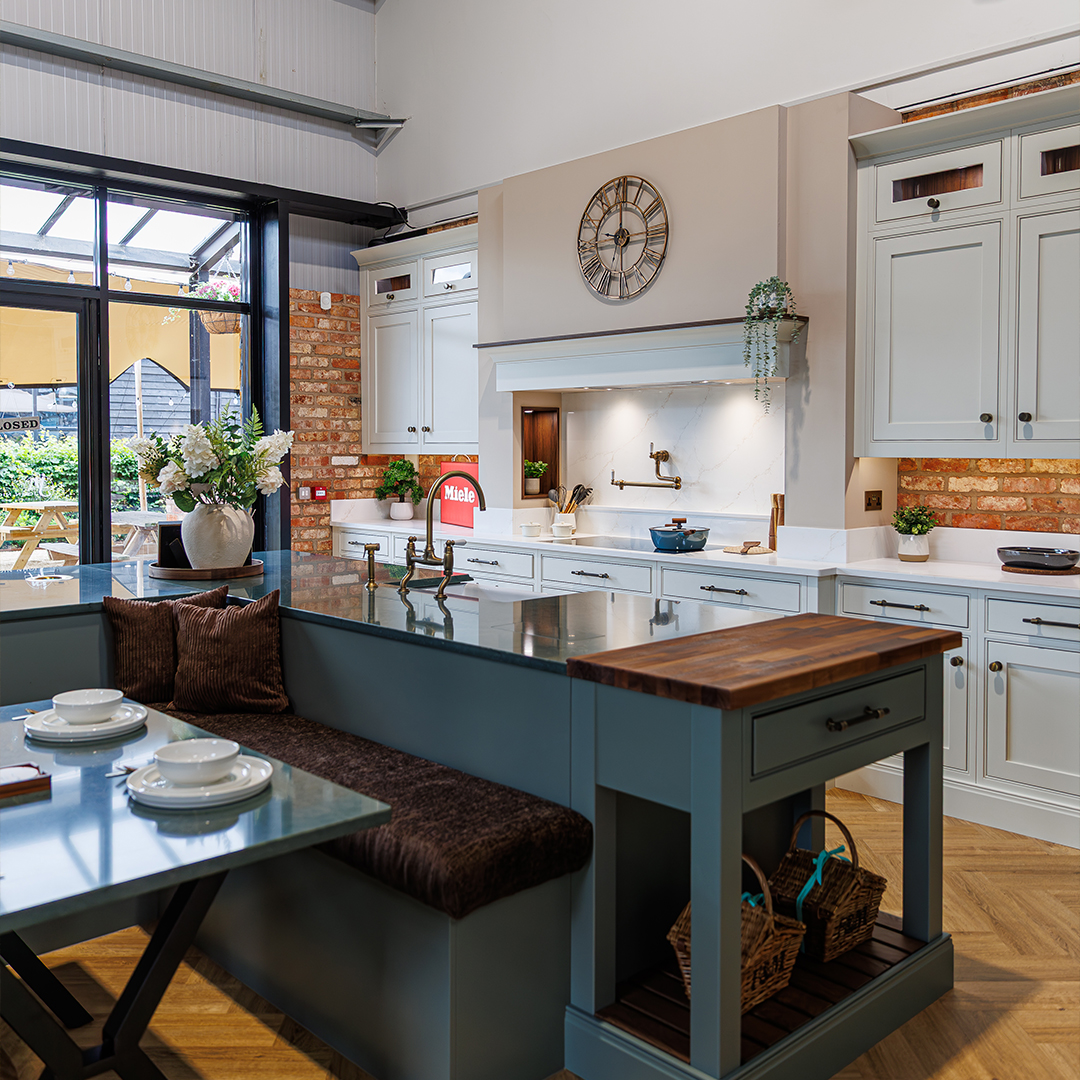 John Nicholls kitchen showroom in Towcester, featuring a traditional display kitchen with island seating, fitted cabinetry and exposed brick details.