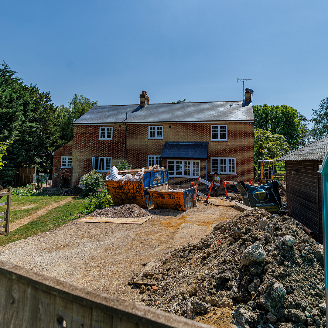 Burgess Building Maintenance carrying out a full renovation and extension of a detached brick property, with excavation work, skips and construction materials on site.
